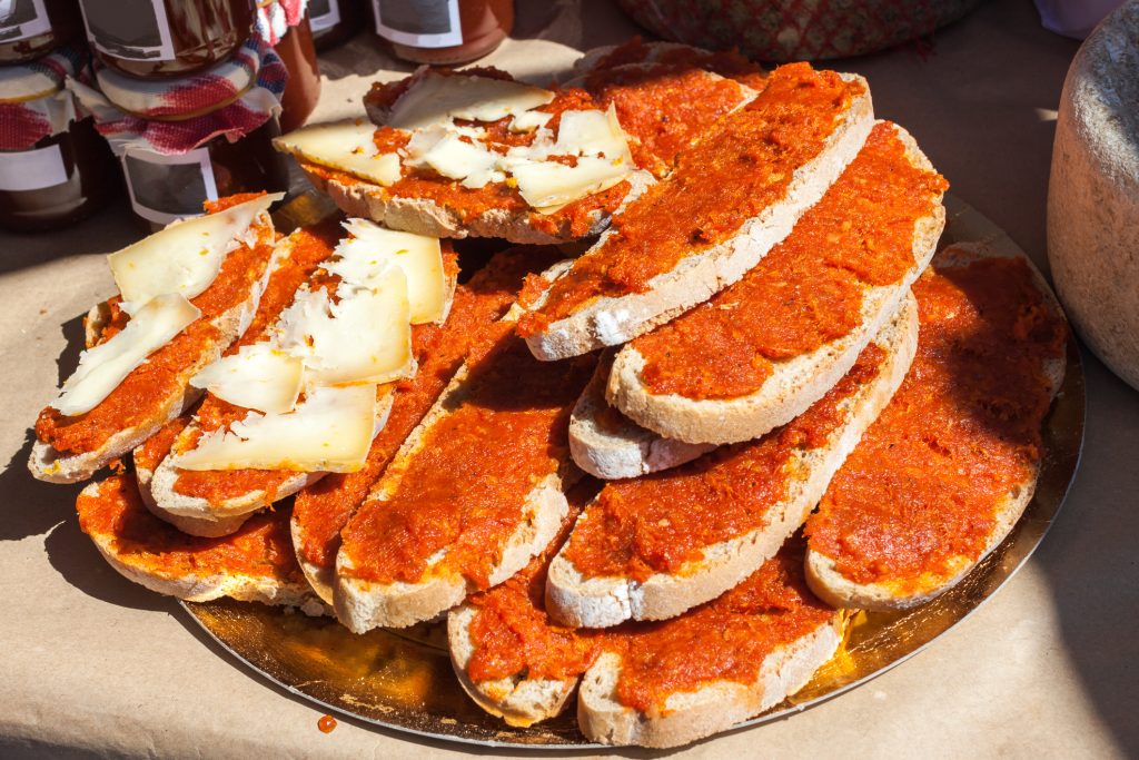 Rustikale Brotscheiben mit Sobrasada-Aufstrich und Käsestreifen auf einem Marktstand