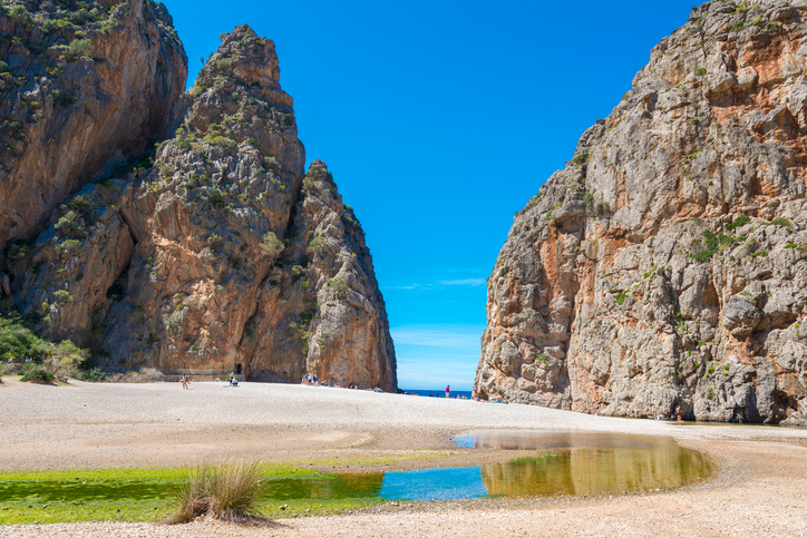 Weitläufiger Kiesstrand zwischen steilen Felswänden des Torrent de Pareis mit Blickrichtung Meer.