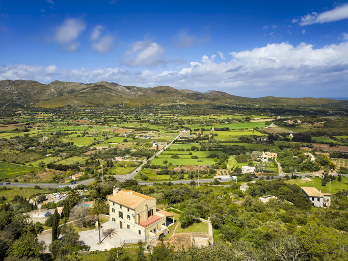 Panoramablick vom Castell de Capdepera auf grüne Felder, Hügel und typische Landhäuser auf Mallorca.
