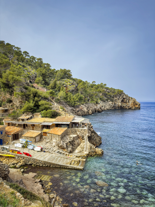 Kleine Bucht mit Bootshäusern, Felsen und türkisfarbenem Wasser bei Deià auf Mallorca.