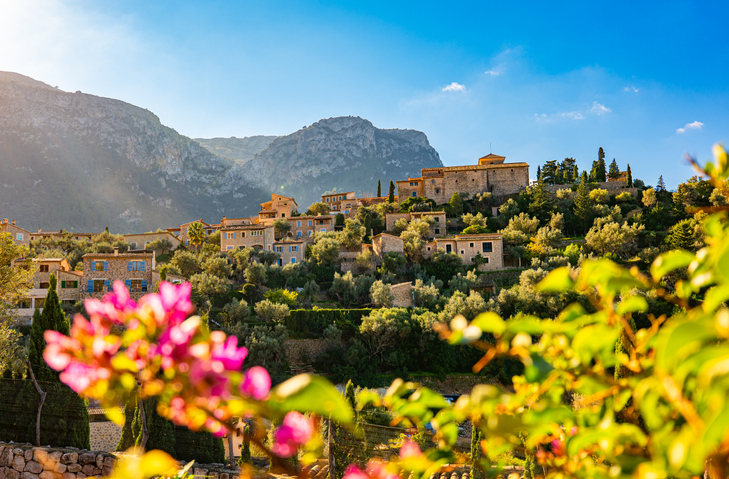Bergdorf Deià auf Mallorca mit Sandsteinhäusern und mediterraner Vegetation im Abendlicht vor der Serra de Tramuntana.