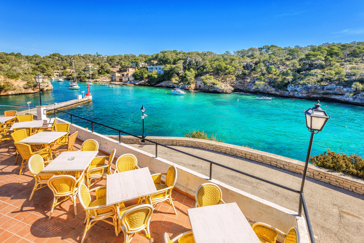 Aussicht von einem Terrassencafé auf die türkisfarbene Bucht und die Felsküste von Cala Figuera