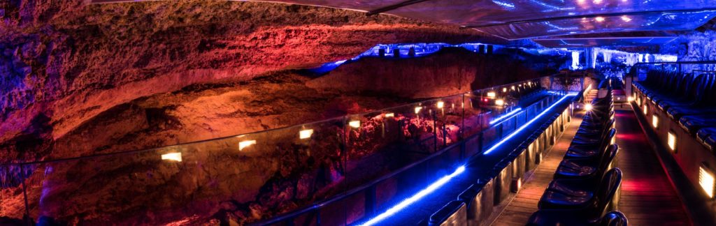 Beleuchteter Veranstaltungssaal in den Höhlen von Hams mit Sitzreihen und Lichtinstallation