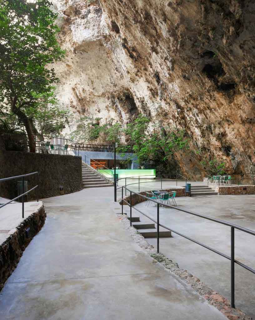 Zugang zur Rundhöhle der Cuevas dels Hams mit Sitzgelegenheiten und Natursteinwänden