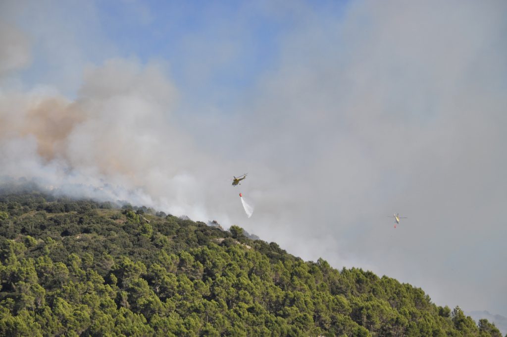 Zwei Löschhubschrauber bekämpfen einen Waldbrand über einem bewaldeten Hügel auf Mallorca