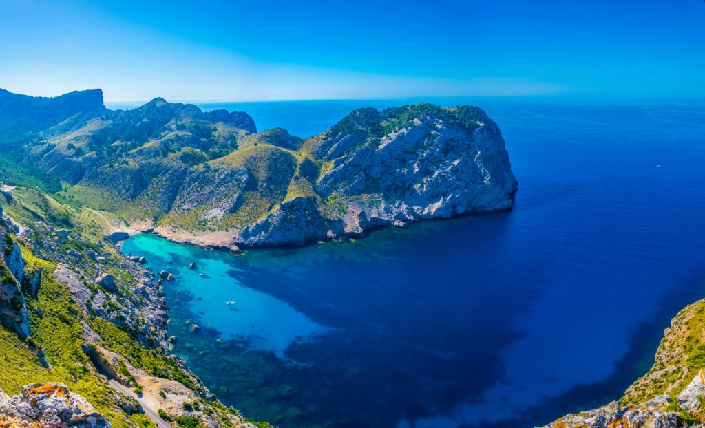 Panoramablick auf die türkisfarbene Bucht Cala Figuera mit umliegenden grünen Bergen und tiefblauem Mittelmeer, nahe Cap Formentor auf Mallorca.