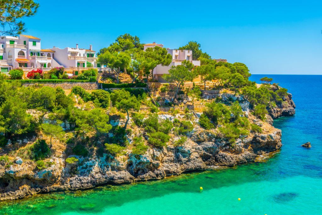 Klippen von Cala Pi mit mediterranen Häusern und türkisblauem Wasser unter klarem Himmel auf Mallorca