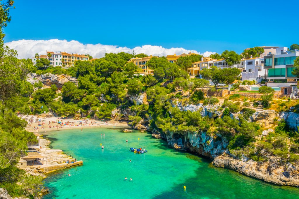 Blick auf die idyllische Badebucht Cala Pi mit Sandstrand, Felsen und grüner Vegetation auf Mallorca