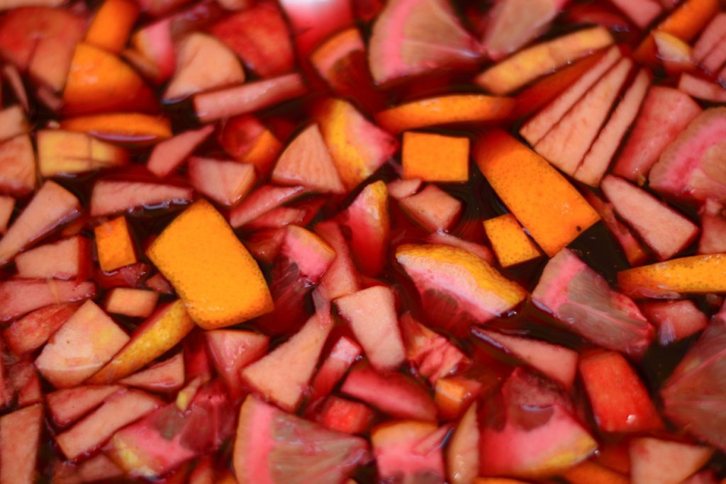 Nahaufnahme von Sangria mit schwimmenden Orangen-, Apfel- und Zitronenstücken.