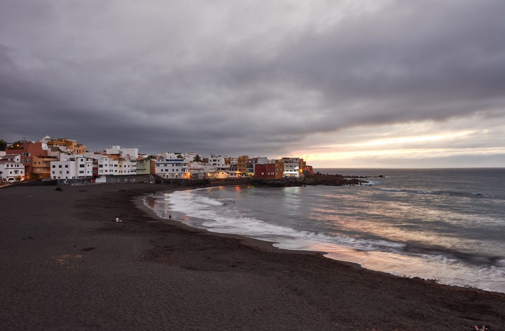 Playa Jardín auf Teneriffa mit schwarzem Sandstrand, bunten Häusern am Meer und Abendstimmung in Puerto de la Cruz.