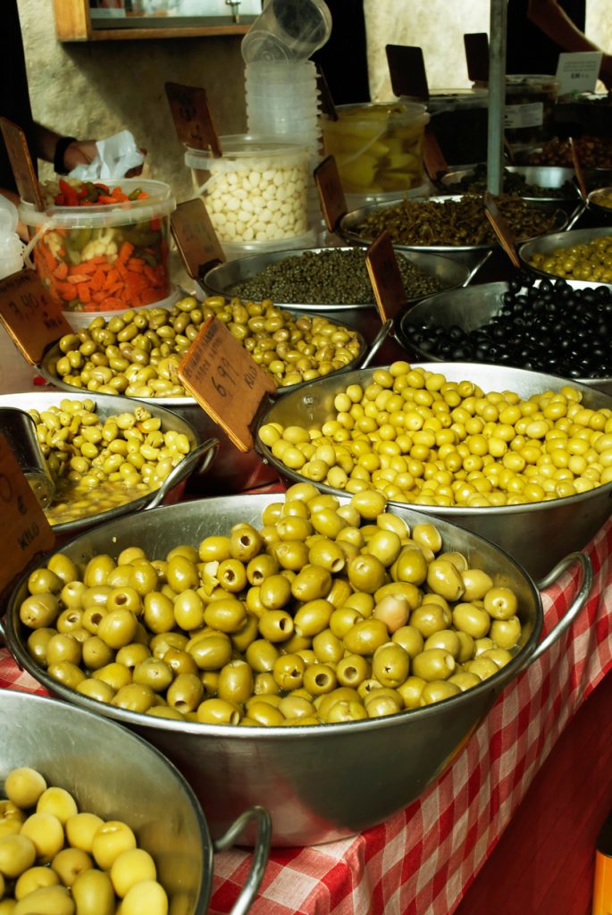 Verschiedene Sorten frischer Oliven in Metallschalen auf dem Wochenmarkt in Pollença, Mallorca.