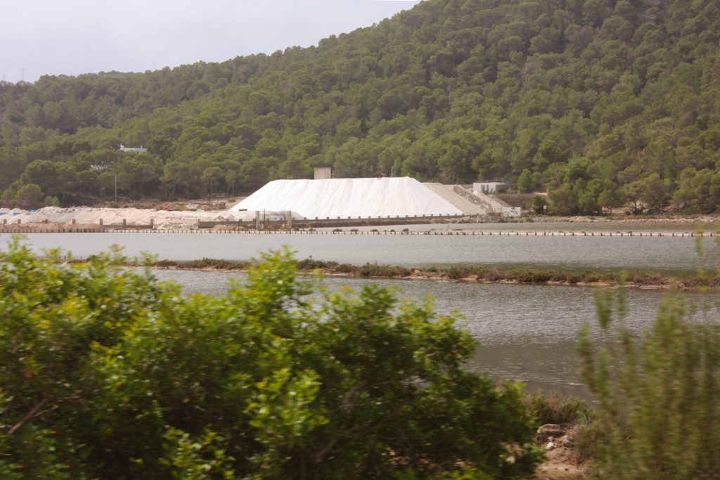 Salzberge in den Salinen von Ses Salines auf Ibiza, umgeben von Natur und Wasserflächen.