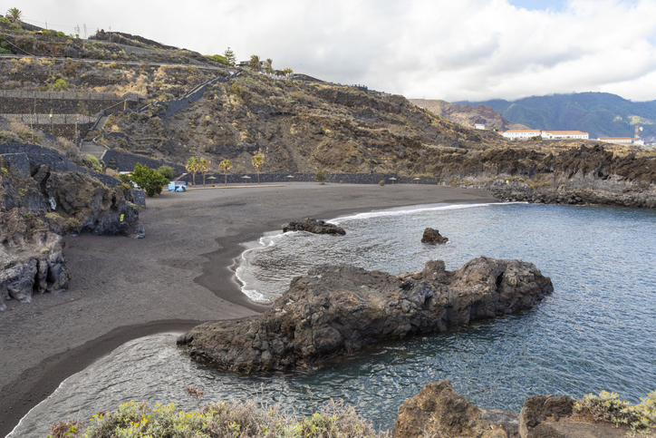 Blick auf den dunklen Sandstrand Playa de los Cancajos mit Lavagestein und türkisblauem Wasser