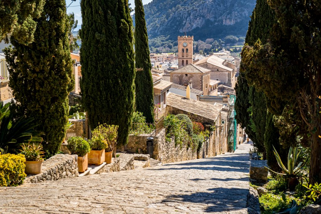 Treppe zum Kalvarienberg in Pollença, gesäumt von Zypressen und mit Blick auf Kirche und Altstadt im Norden von Mallorca