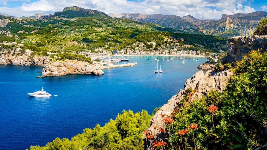 Panoramablick auf die geschützte Bucht von Port de Sóller mit Booten und grüner Berglandschaft im Hintergrund