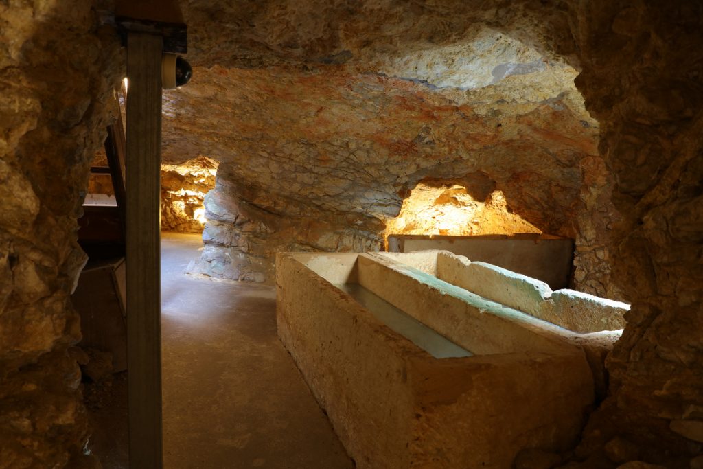 Unterirdische Grabkammern in der Nekropole Puig des Molins auf Ibiza mit alten Sarkophagen in Felsräumen.