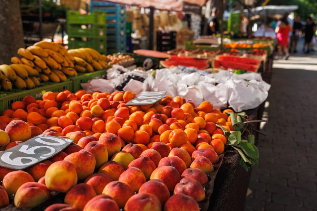 Pfirsiche, Aprikosen und Bananen an einem Obststand auf dem Wochenmarkt in Alcudia auf Mallorca.