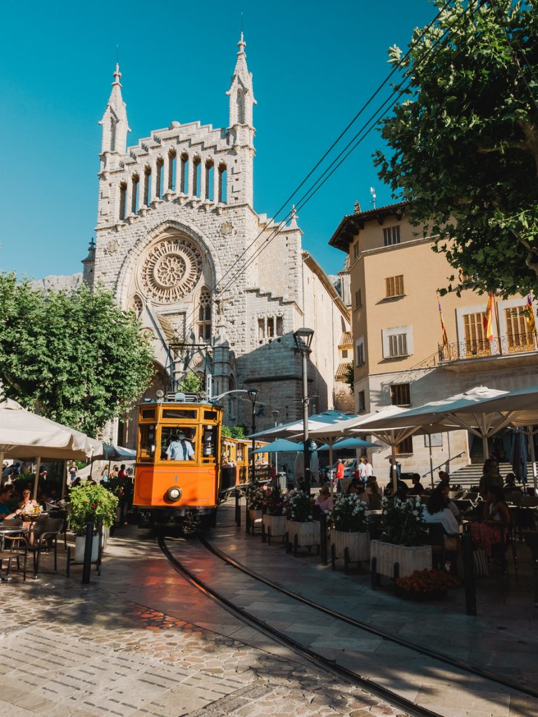 Historische Straßenbahn fährt durch das Zentrum von Sóller vor der Kirche Sant Bartomeu auf Mallorca.