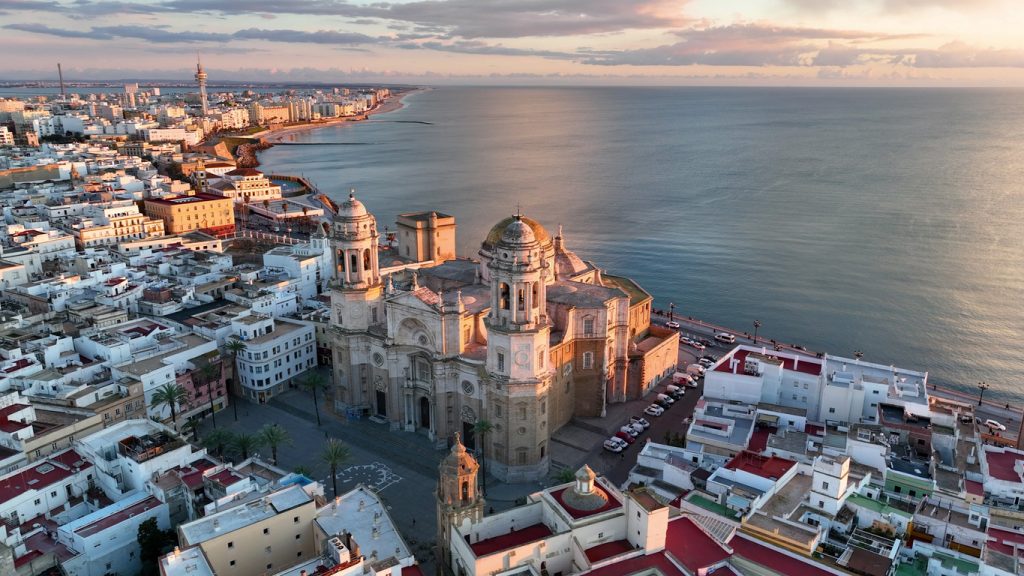 Luftaufnahme der Kathedrale von Cádiz mit Blick auf die Küste und die Altstadt bei Sonnenuntergang.