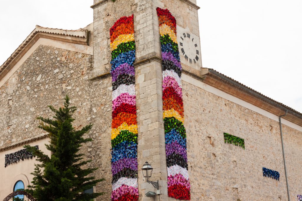 Traditionelle Kirche in Costitx auf Mallorca mit kunstvoller floraler Fassadendekoration in Regenbogenfarben