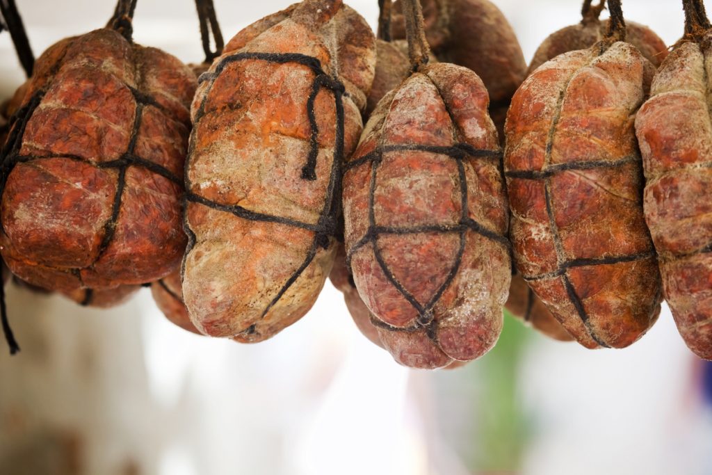Mehrere Sobrasada-Würste hängen zum Trocknen, traditionelle Spezialität aus Mallorca.