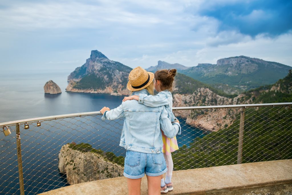 Mutter mit Kind genießt die Aussicht vom Mirador de El Colomer auf Mallorca mit Blick auf das Meer und die dramatische Felsküste