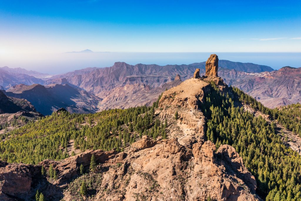Landschaft auf Gran Canaria mit dem markanten Felsen Roque Nublo, umgeben von Bergen und Wäldern.