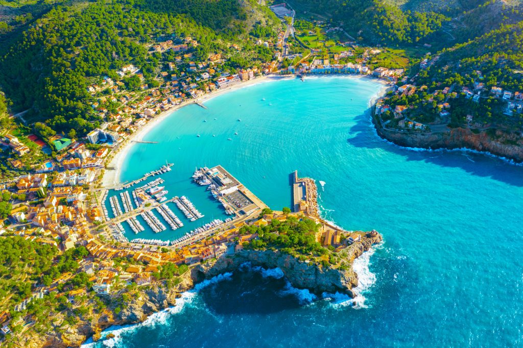 Panoramablick auf den Hafen von Port de Sóller mit türkisblauem Wasser, umgeben von Bergen und mediterraner Bebauung auf Mallorca