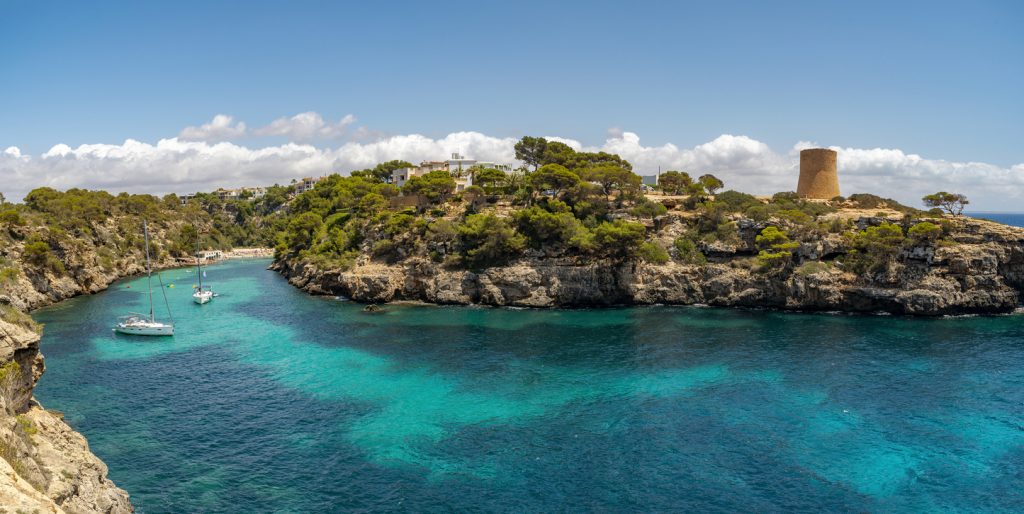 Panoramablick auf Cala Pi nahe Llucmajor auf Mallorca mit türkisfarbenem Wasser, Klippen und historischem Wachturm.