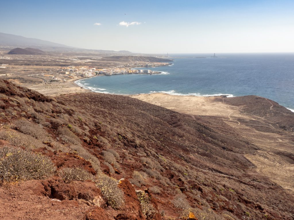 Blick von der Montaña Roja auf Playa de El Médano auf Teneriffa mit weitem Sandstrand, Dünenlandschaft und Küstenlinie am Atlantik.