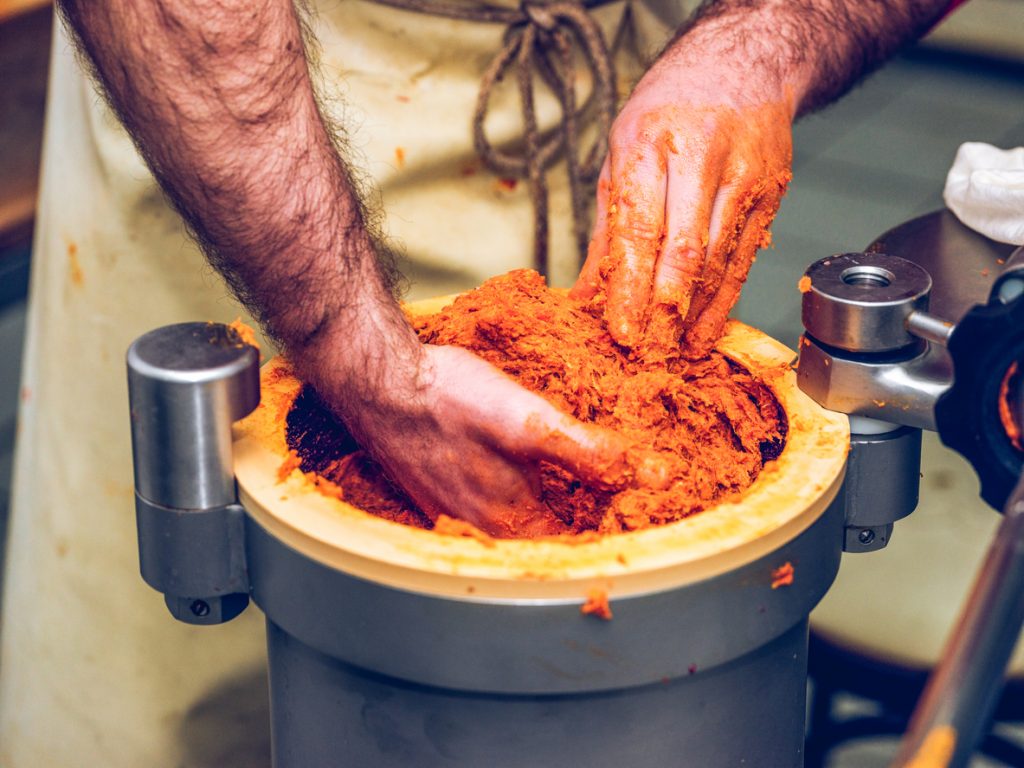 Hände eines Handwerkers bei der Zubereitung von Sobrasada, der typischen Paprika-Streichwurst aus Mallorca.