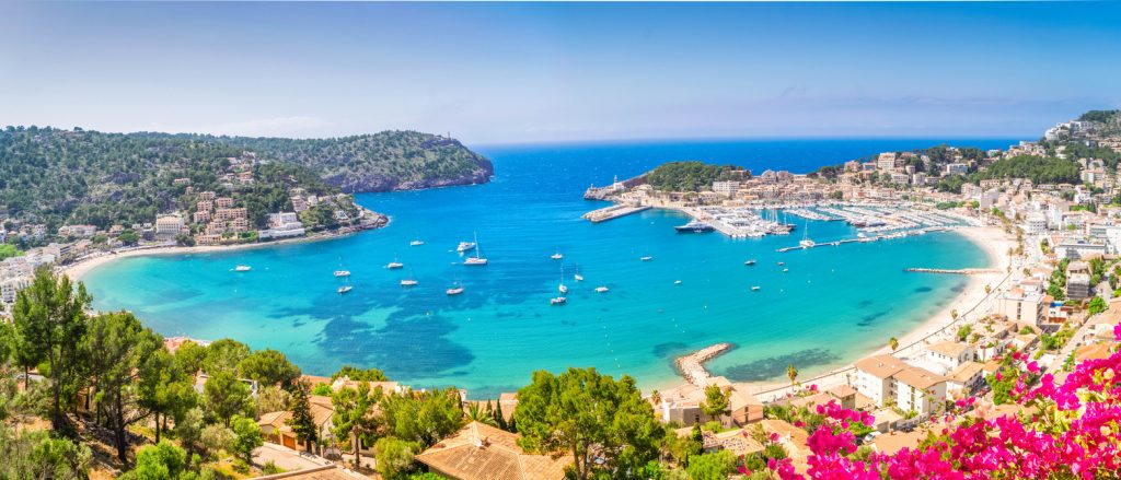 Panoramablick auf Port de Sóller mit Hafen, Segelbooten und türkisblauem Meer auf Mallorca.