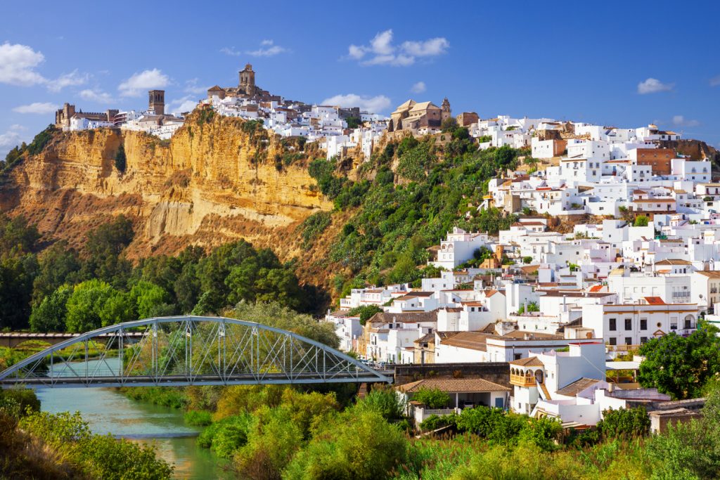 Panoramablick auf Arcos de la Frontera in der Provinz Cádiz mit weißen Häusern auf einem Felsen und einer Brücke über den Fluss.