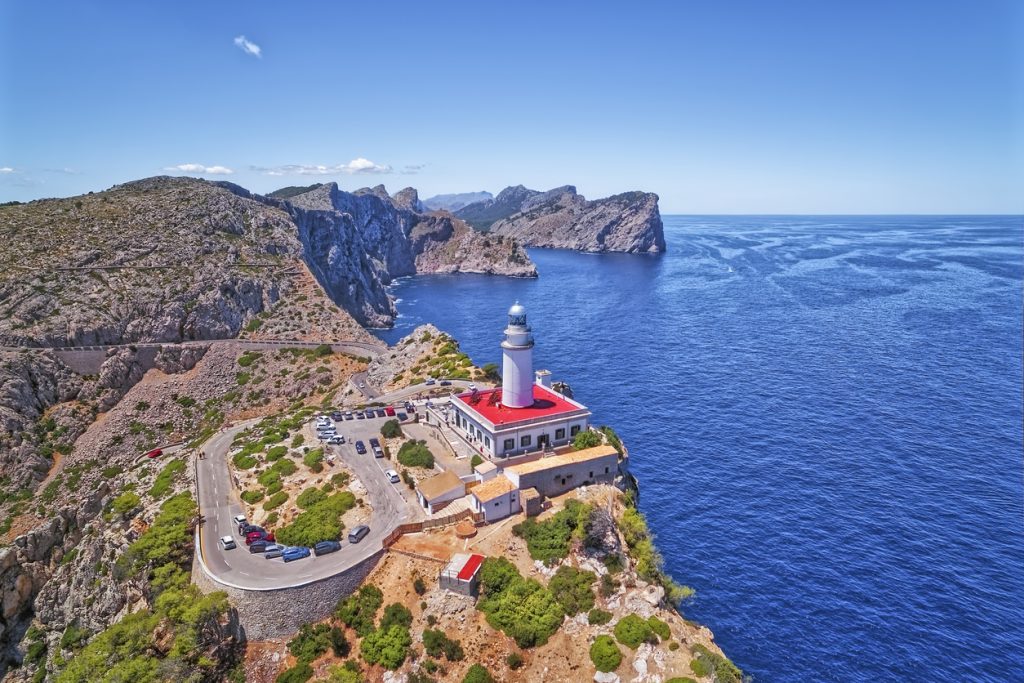 Drohnenaufnahme des Leuchtturms am Cap Formentor auf Mallorca mit Blick auf das tiefblaue Mittelmeer und die felsige Küstenlandschaft.