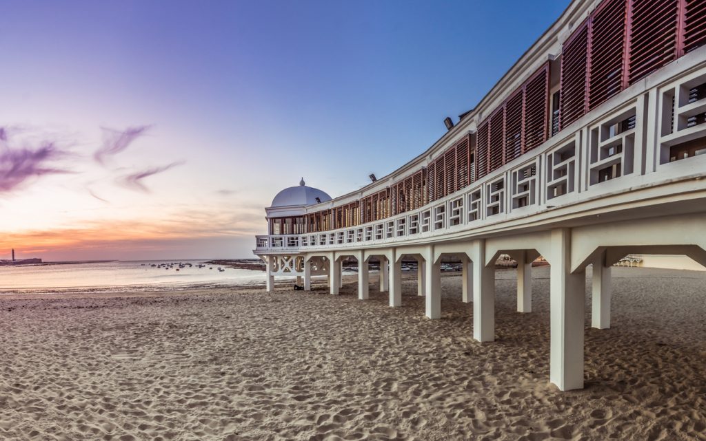 Strand La Caleta in Cádiz mit dem historischen Pavillon am Abendhimmel.