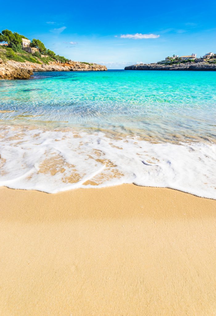 Blick vom Strand Cala Marçal auf das klare türkisfarbene Wasser und die umliegenden Felsen bei Portocolom, Mallorca.