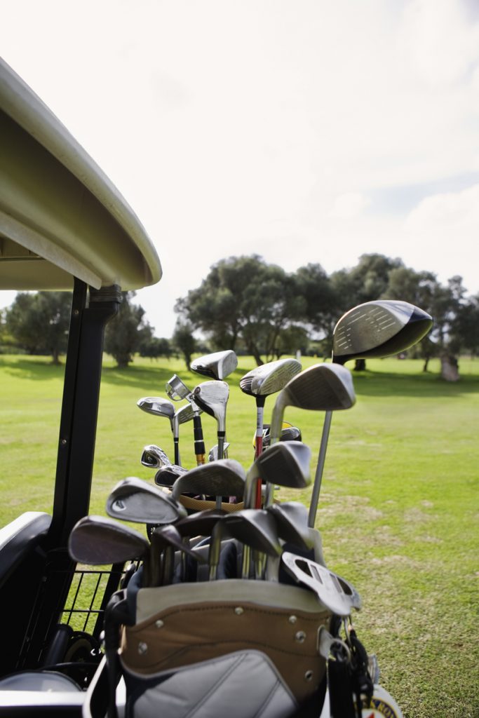 Nahaufnahme eines Golfbags mit verschiedenen Golfschlägern auf einem Golfplatz auf Mallorca, im Hintergrund grüne Fairways und Bäume.