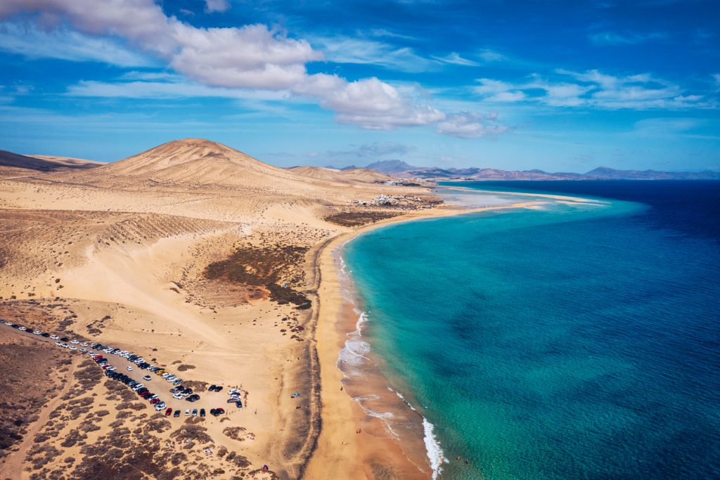 Luftaufnahme des Playa de Sotavento auf Fuerteventura mit endlosem Sandstrand, türkisblauem Wasser und Dünenlandschaft.