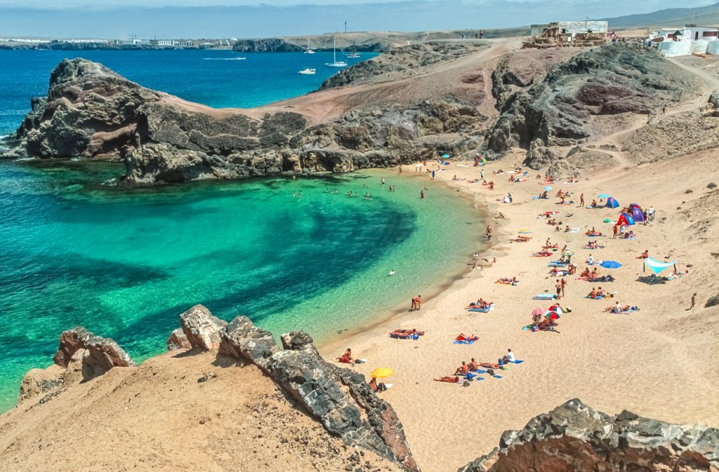 Strand Playa de Papagayo auf Lanzarote mit goldenem Sand und kristallklarem türkisblauem Meer.