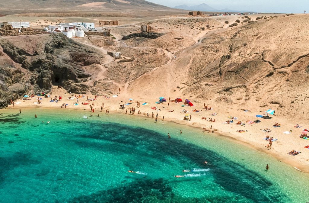 Playa de Papagayo auf Lanzarote mit goldenem Sandstrand und kristallklarem türkisfarbenem Meer.