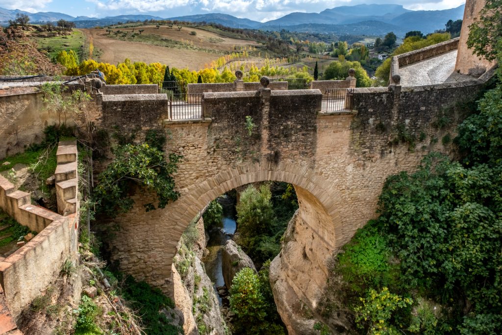 Ronda Puente Viejo – Steinbrücke über Schlucht mit Landschaft und Bergen