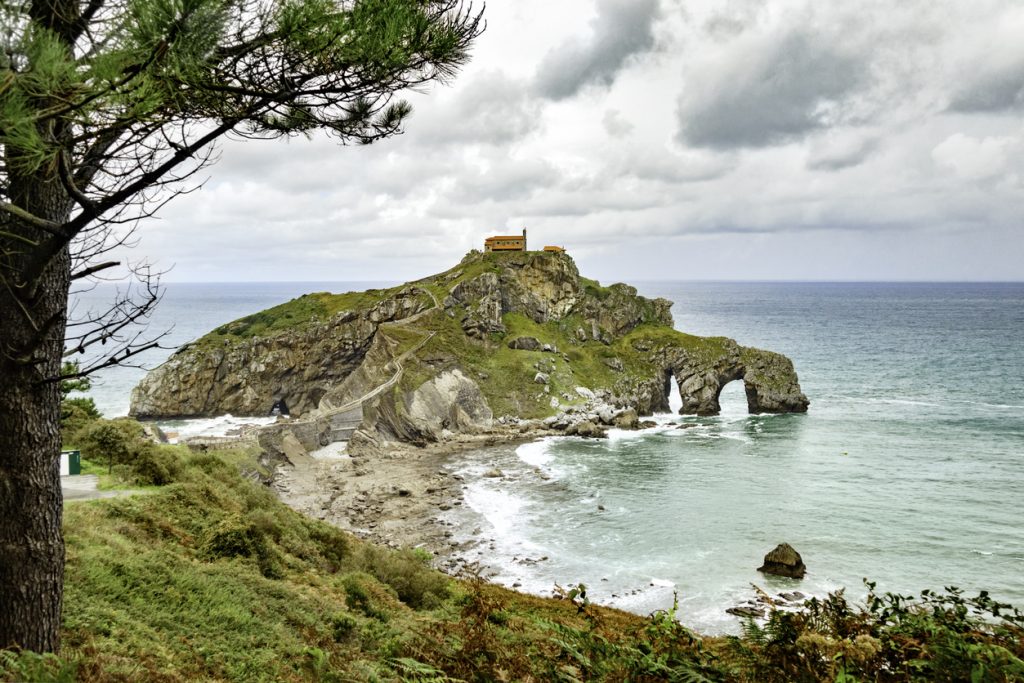 Panoramablick auf San Juan de Gaztelugatxe mit der Kapelle auf der Felseninsel im Baskenland, verbunden durch eine schmale Treppe und umgeben vom Atlantik.