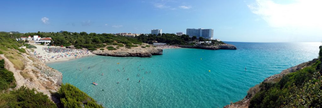 Panoramablick auf die Cala Domingos (Gran und Petit) mit hellen Sandstränden, türkisfarbenem Meer und Hotels auf den Klippen.