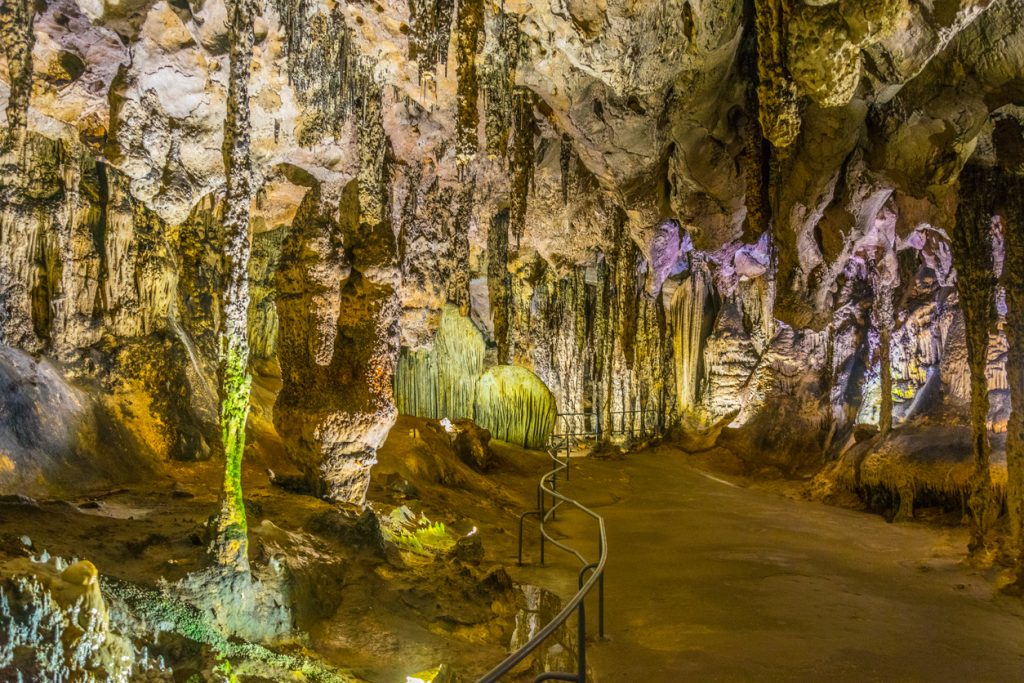 Höhlenraum mit Stalaktiten, Stalagmiten und Geländerweg.