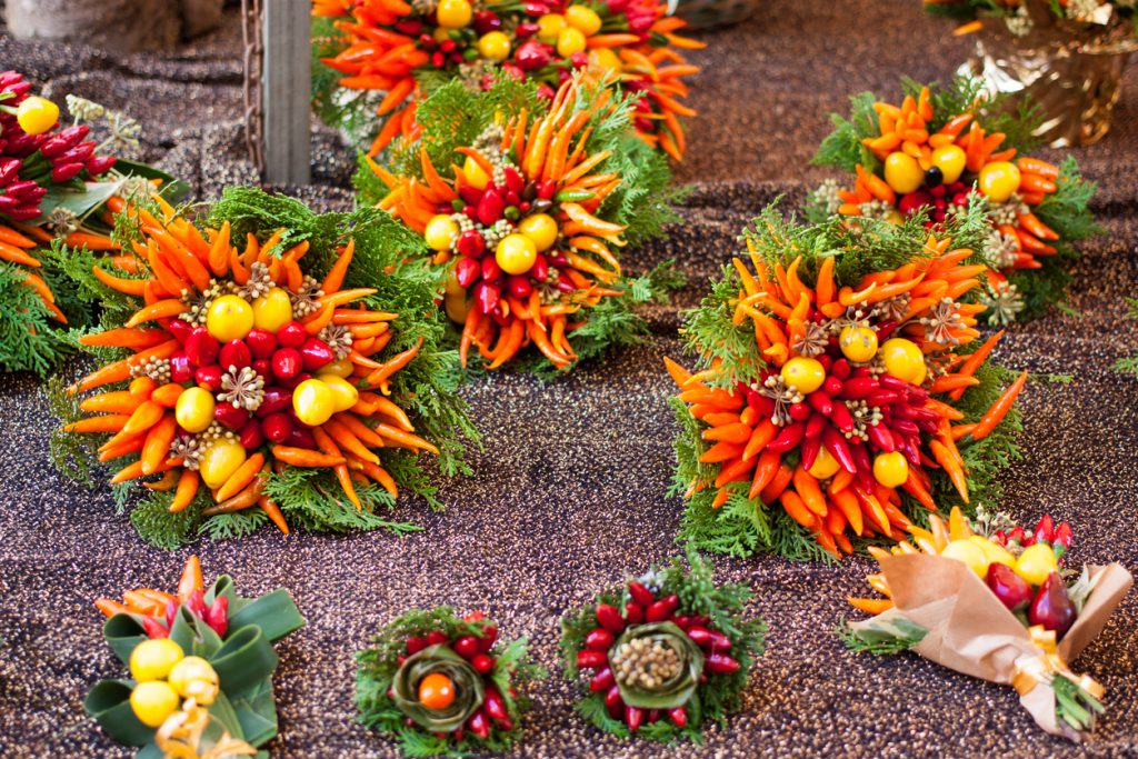 Farbige Kränze aus Chilis, kleinen Zitrusfrüchten und Grün liegen auf einem Marktstand in Porreres.