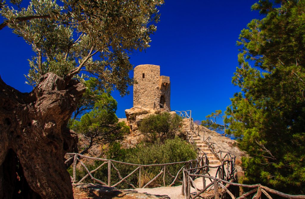 Steinerner Rundturm auf Fels, erreichbar über Treppe mit Holzgeländer.