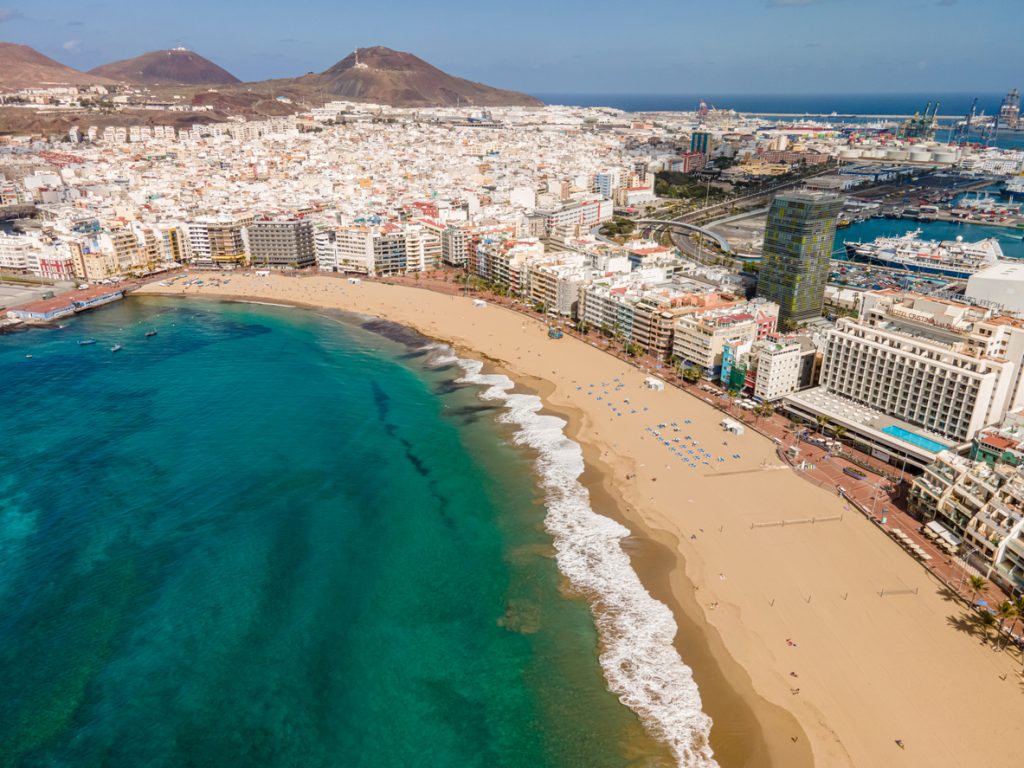Weitläufiger Sandstrand mit ruhigem Wasser, Promenade und Badegästen in Las Palmas.