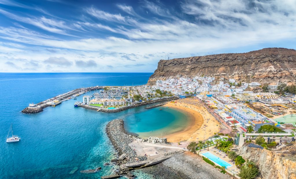 Blick auf Puerto de Mogán mit Marina, geschützter Sandbucht und hohen Felsklippen.