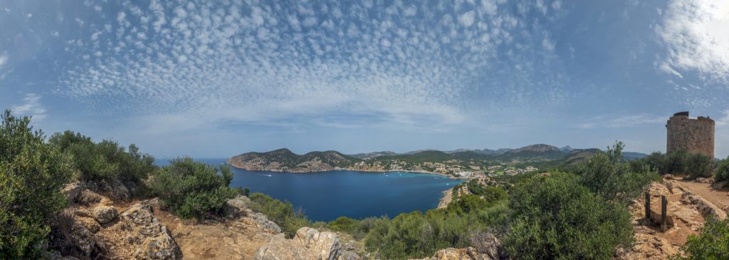 Blick vom Torre de Cap Andritxol über die Bucht, Küstenfelsen und den wolkigen Himmel auf Mallorca.