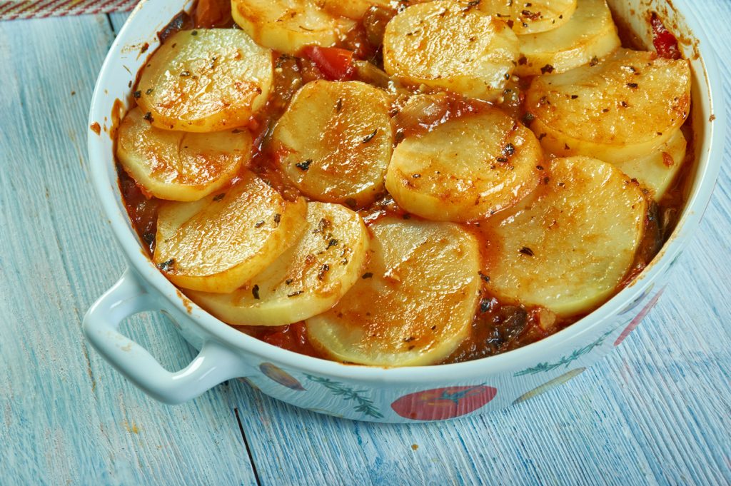 Auflaufform mit in Tomatensoße geschichteten Kartoffelscheiben, Paprika und Aubergine als mallorquinisches Tumbet.